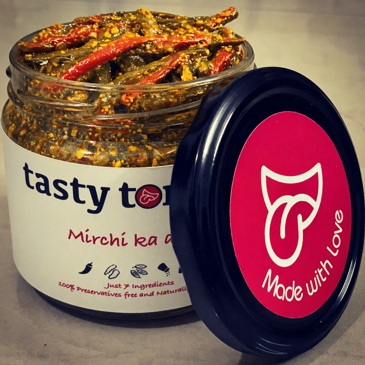 Jar of 'tasty tongue' Mirchi ka achaar with a pink lid on a gray background